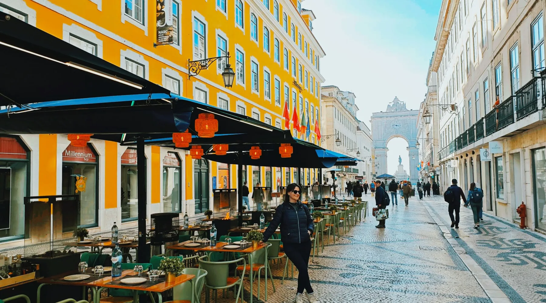 Rua Augusta i Lissabons Baixa, caféterrasser under gule facader til venstre og Rua Augusta-buen for enden af den brostensbelagte gade